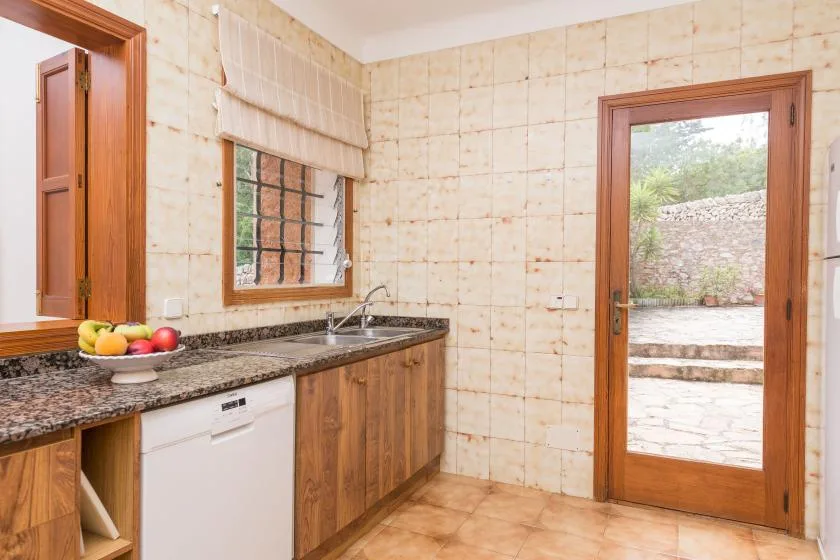 A tiled kitchen with wooden cabinets, a countertop, and a glass-paneled door.