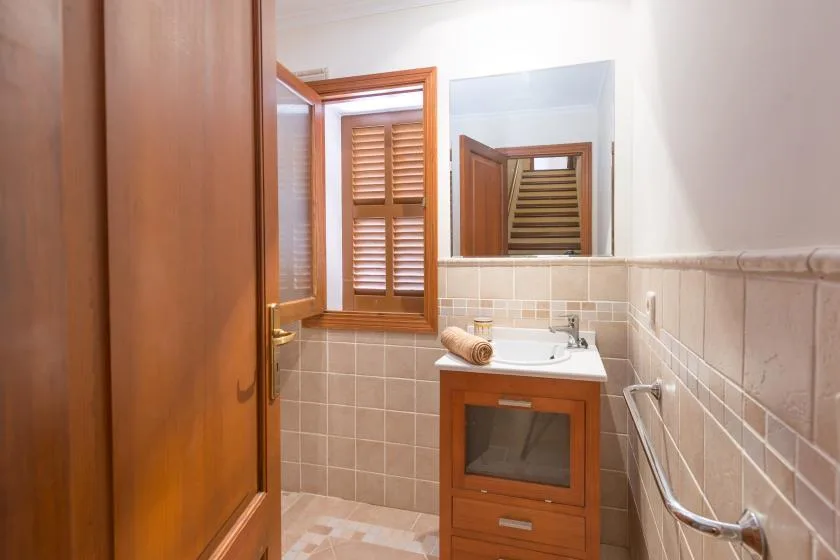 A bathroom with a sink, mirror, and wooden shutters.