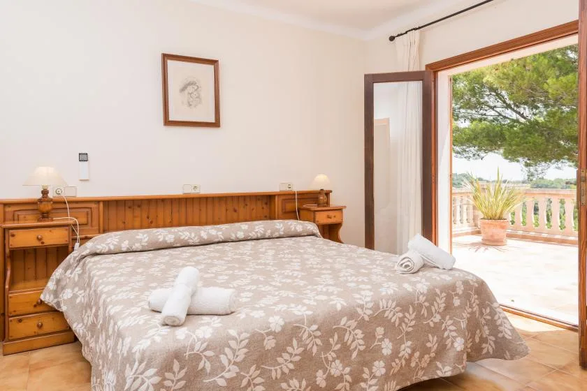 A bedroom with a double bed and an open doorway to a sunlit terrace.