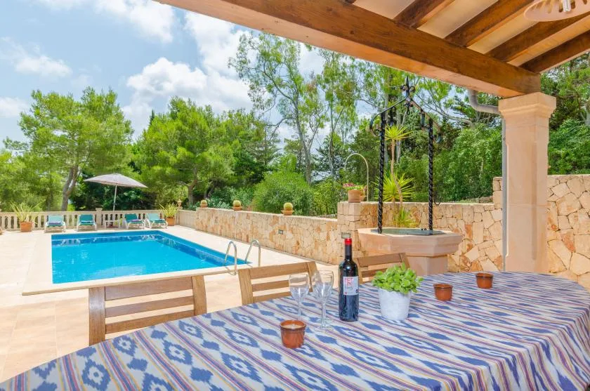 A covered patio dining area overlooks a swimming pool and landscaped garden.