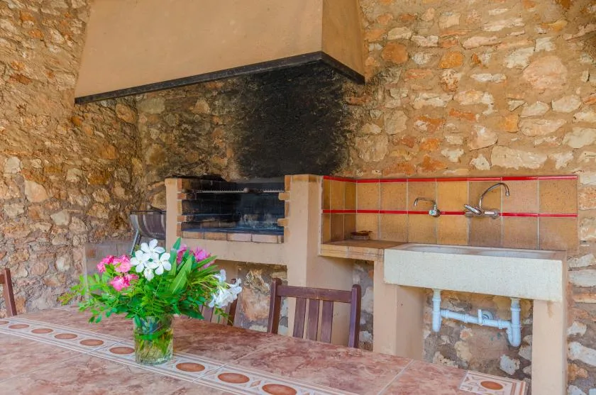 A rustic outdoor kitchen area with a brick grill and sink.
