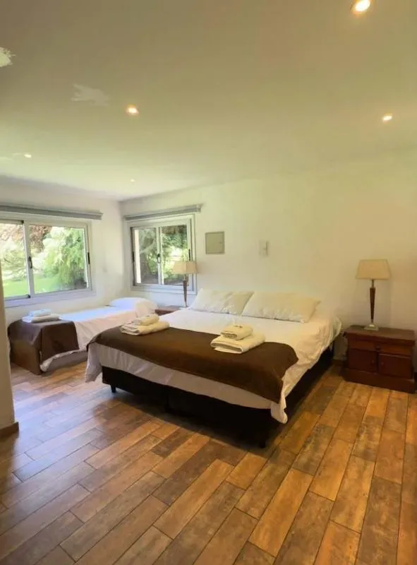 Un dormitorio con una cama grande y ventanas con vistas a la vegetación.