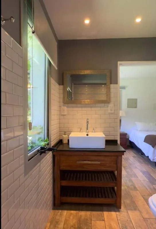 Un lavabo de baño con un lavamanos blanco está junto a una ventana grande.