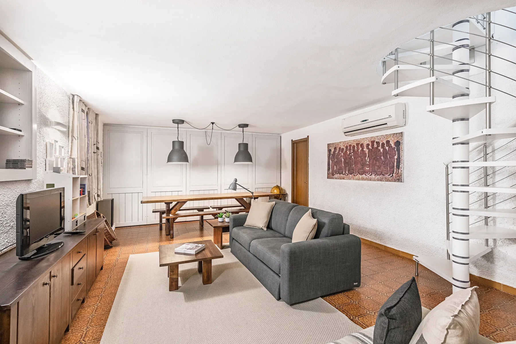 Una sala de estar con un sofá gris, una mesa de centro y un comedor.
