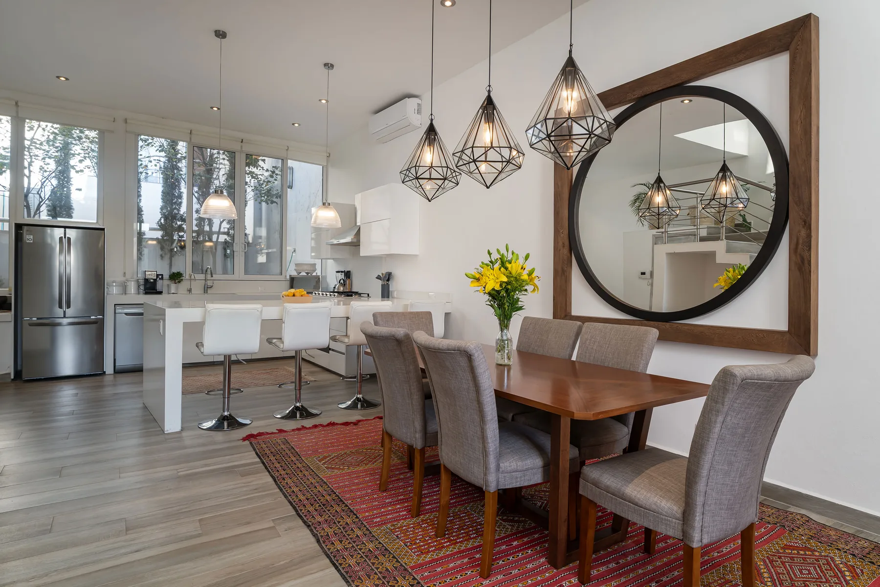 An open-plan kitchen and dining area with a wooden table and pendant lights.