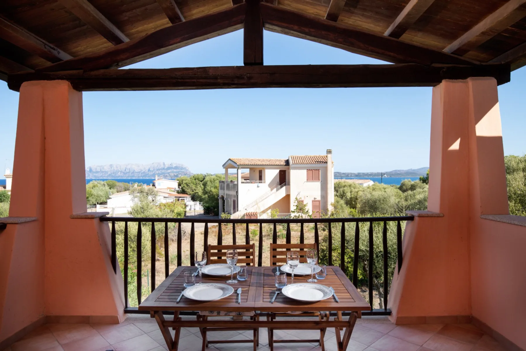 Una zona de comedor en una terraza cubierta ofrece vistas de edificios cercanos y el mar.