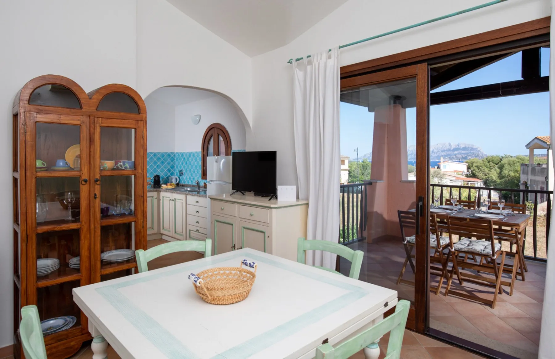 Comedor con una mesa junto a la cocina y puertas abiertas al patio.