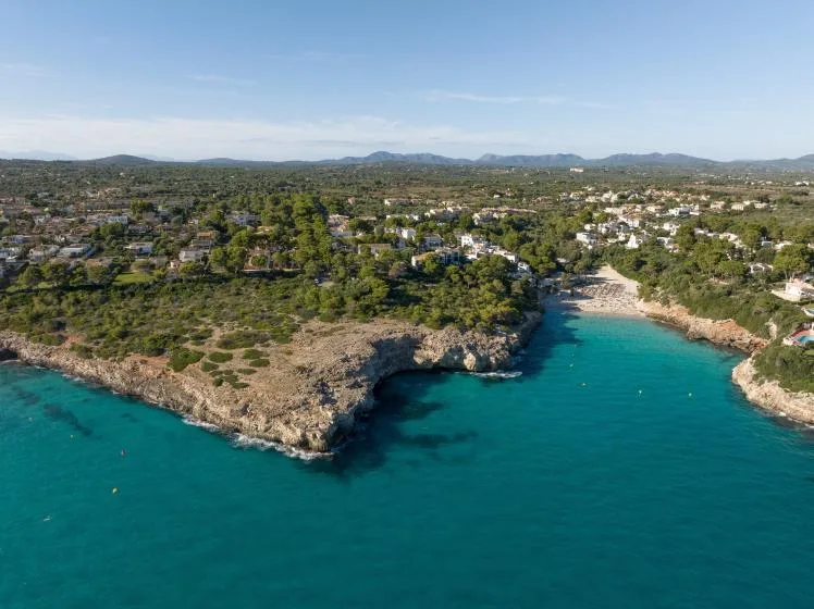 Aerial view of a turquoise coastal inlet bordered by rocky shores and greenery.