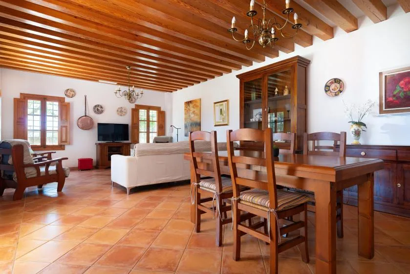 A dining and living room with wooden furniture and a beamed ceiling.