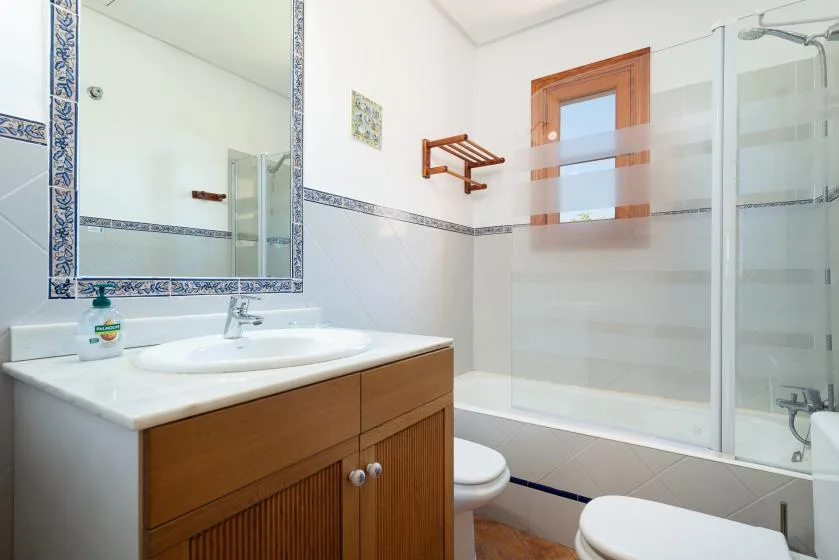 A tiled bathroom with a vanity, mirror, and glass shower.