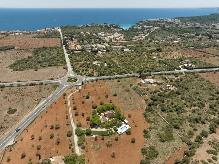 An aerial view shows a coastal settlement, surrounding fields, and a road junction.
