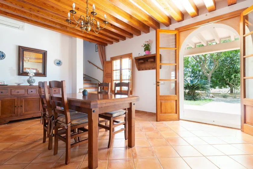 A wooden dining table and chairs sit beside an open doorway to the garden.
