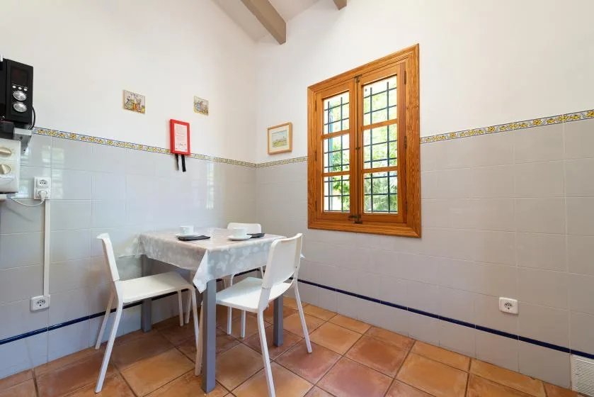 A small dining area with a table and chairs beside a wooden-framed window.