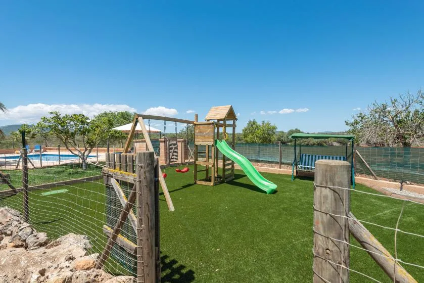 An outdoor play area has a climbing structure and a bright green slide.
