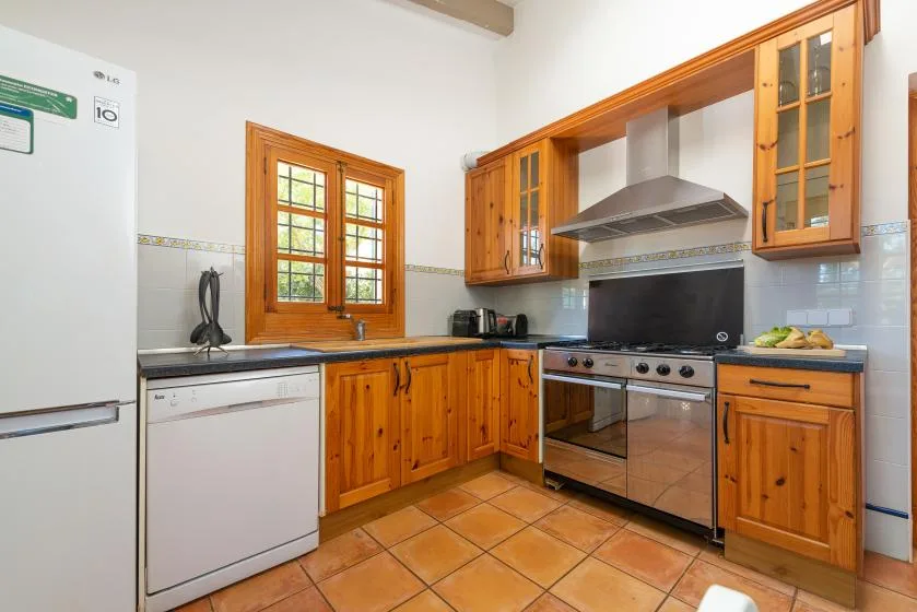 A kitchen with wooden cabinets, a stove, and a window over the sink.