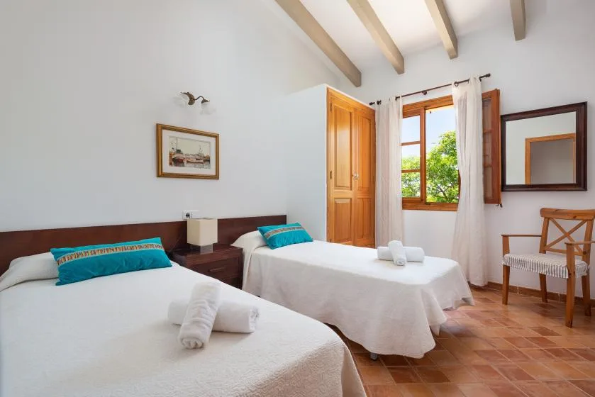 A bright twin bedroom with two beds and a window overlooking greenery.