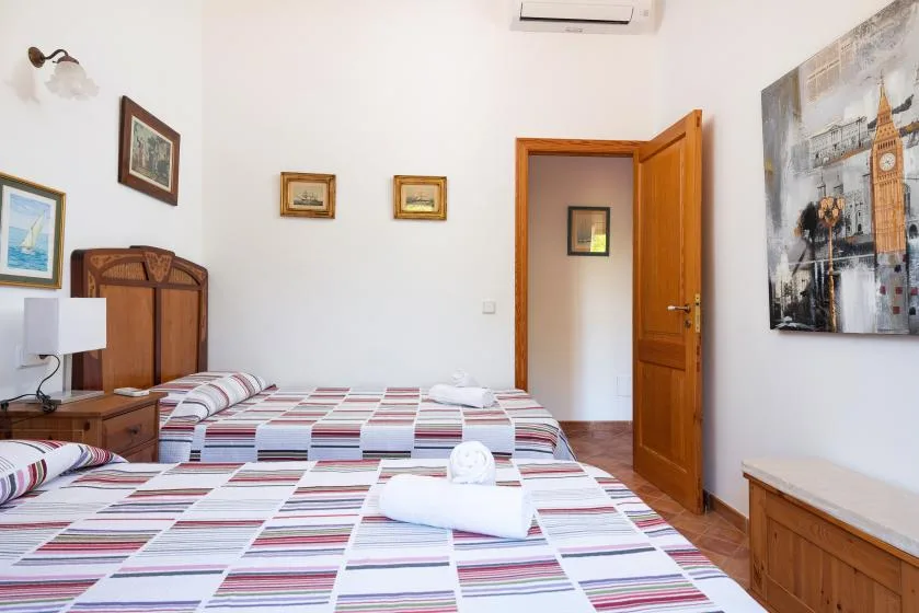 A bedroom with two beds covered in striped bedding and a wooden cabinet.