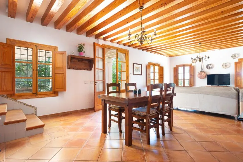 A bright living and dining room with a wooden dining table and seating.