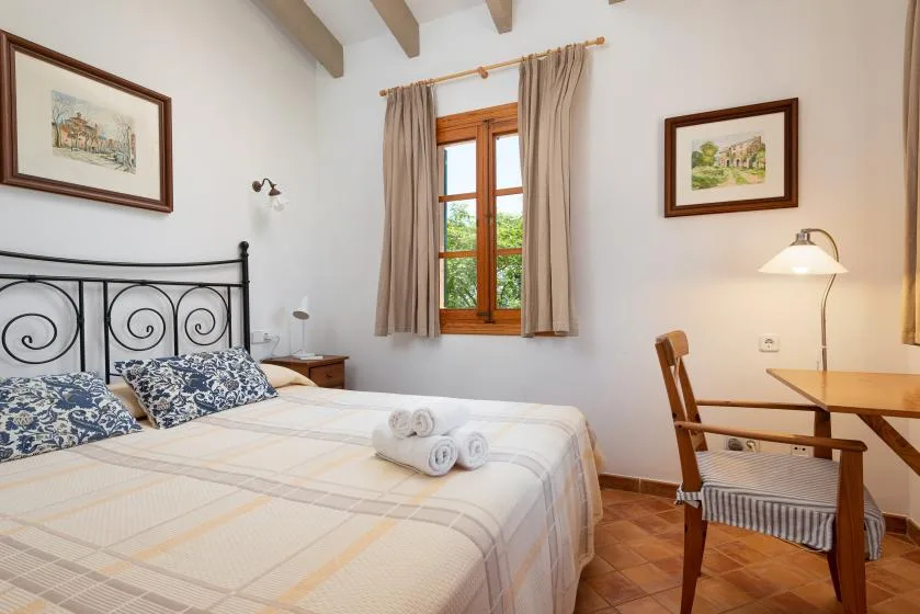 A bright bedroom with a bed beside a wooden-framed window.