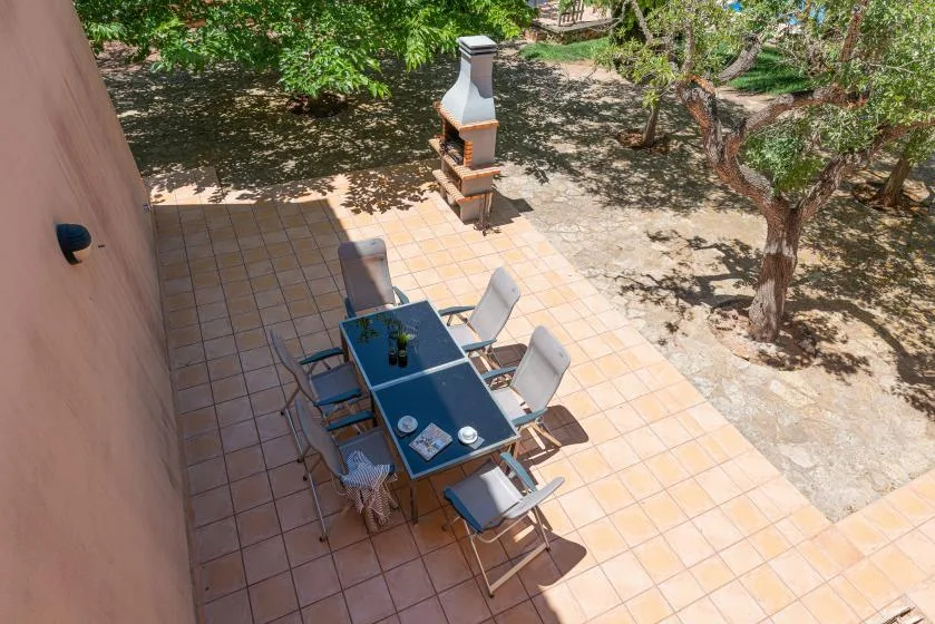 A tiled outdoor patio with a dining table and surrounding trees.