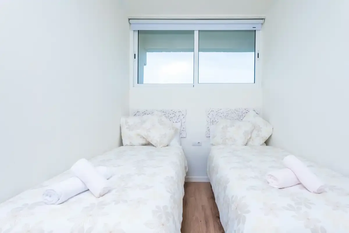 Un dormitorio con dos camas bajo una ventana.