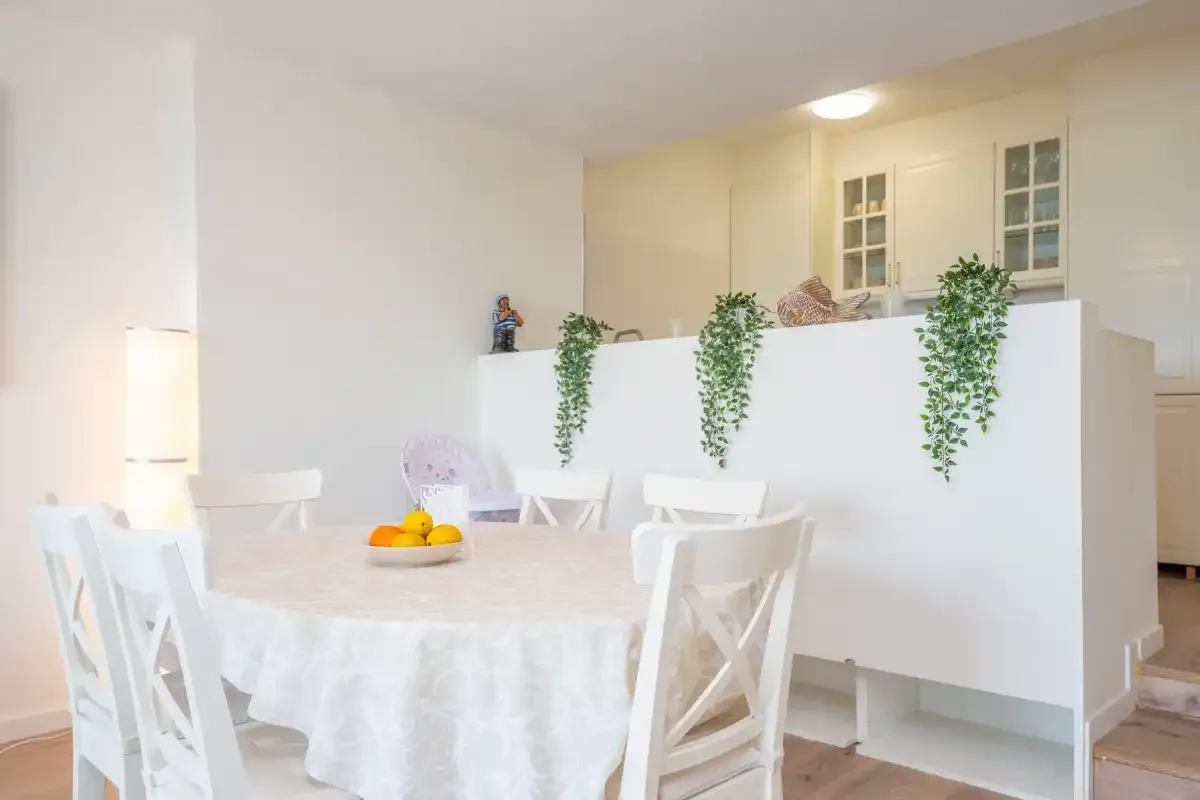 Un comedor luminoso con una mesa redonda y asientos blancos.