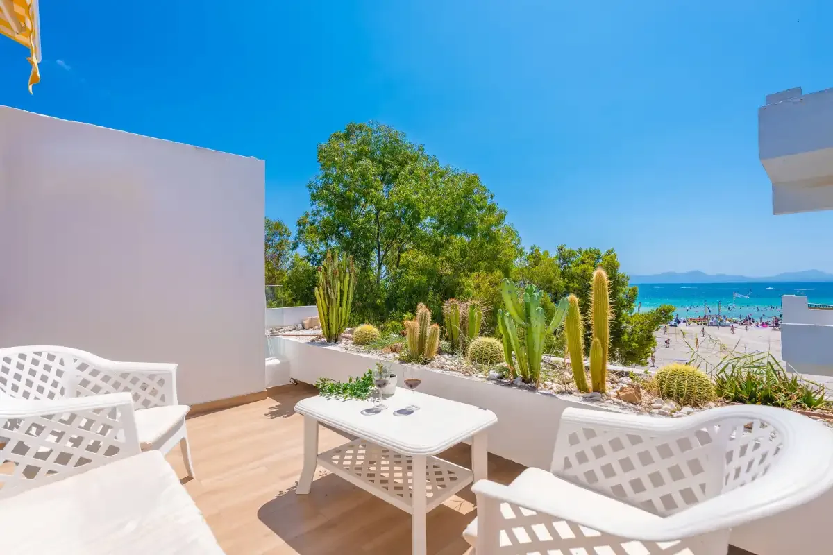 Una terraza soleada con asientos blancos al aire libre y vistas al mar.