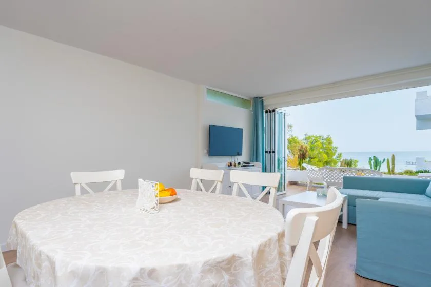 Comedor con una mesa redonda junto a puertas corredizas abiertas hacia una terraza.