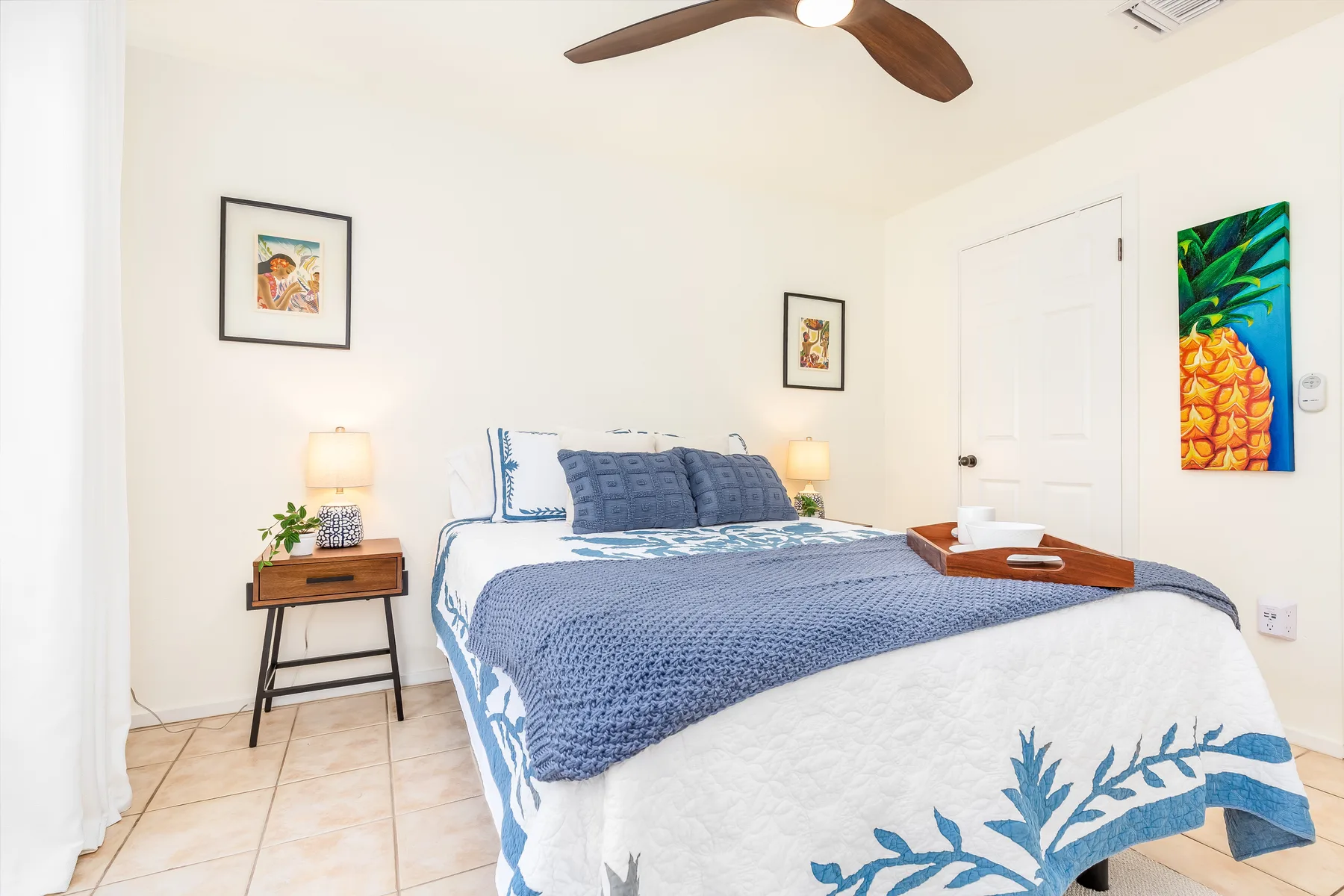 Un dormitorio luminoso con una cama vestida con ropa de cama azul y blanca.