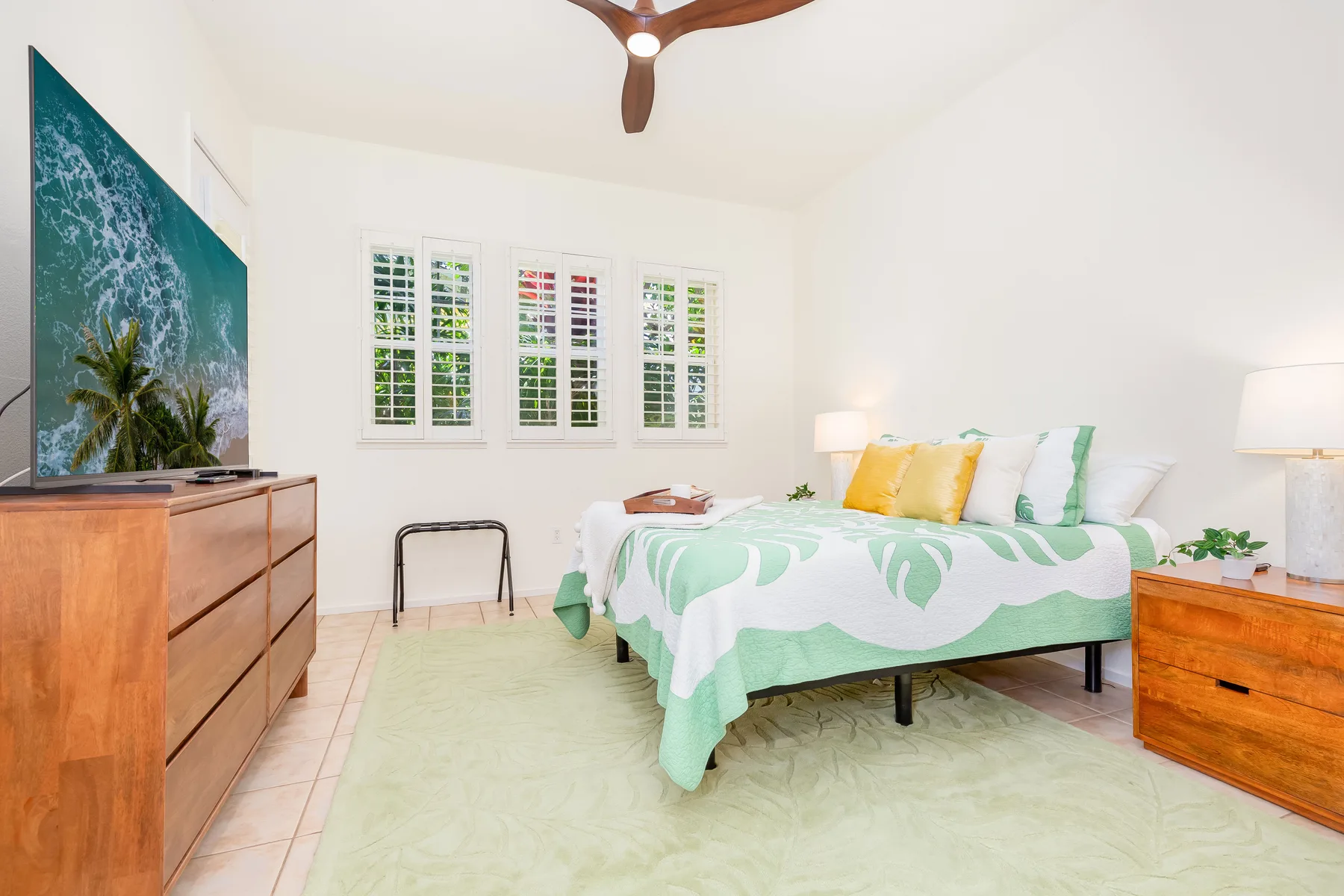 Un dormitorio luminoso con una cama cubierta con ropa de cama verde y blanca.