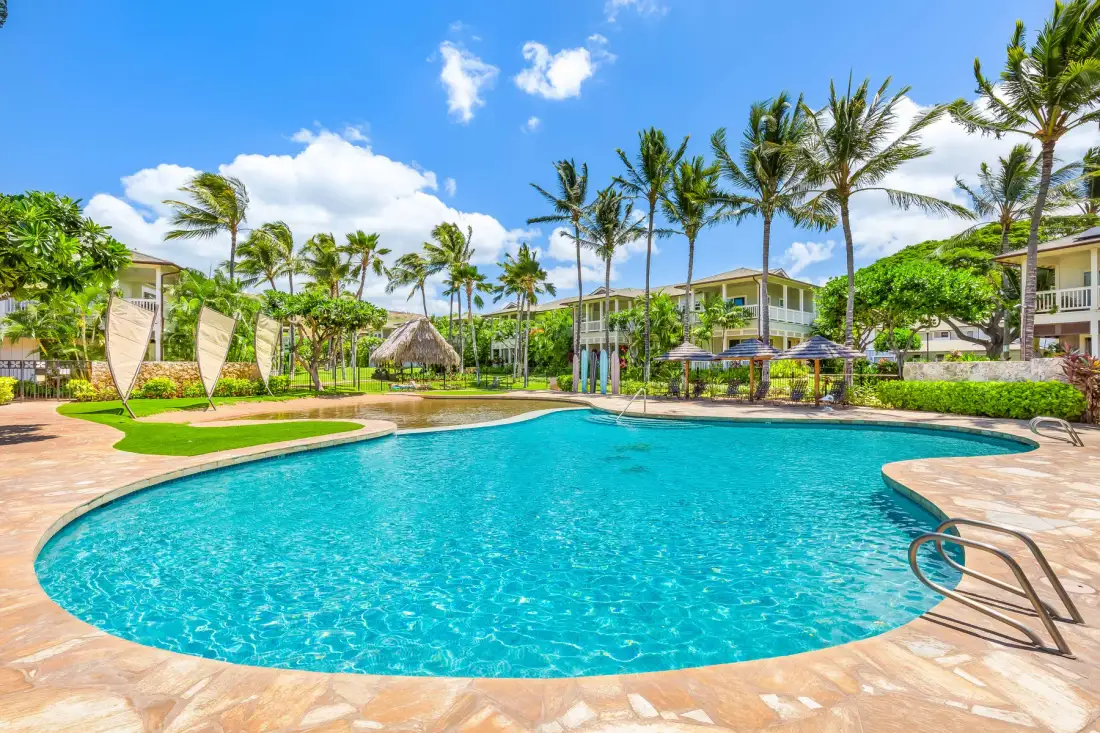 Una piscina de resort rodeada de palmeras y jardines.