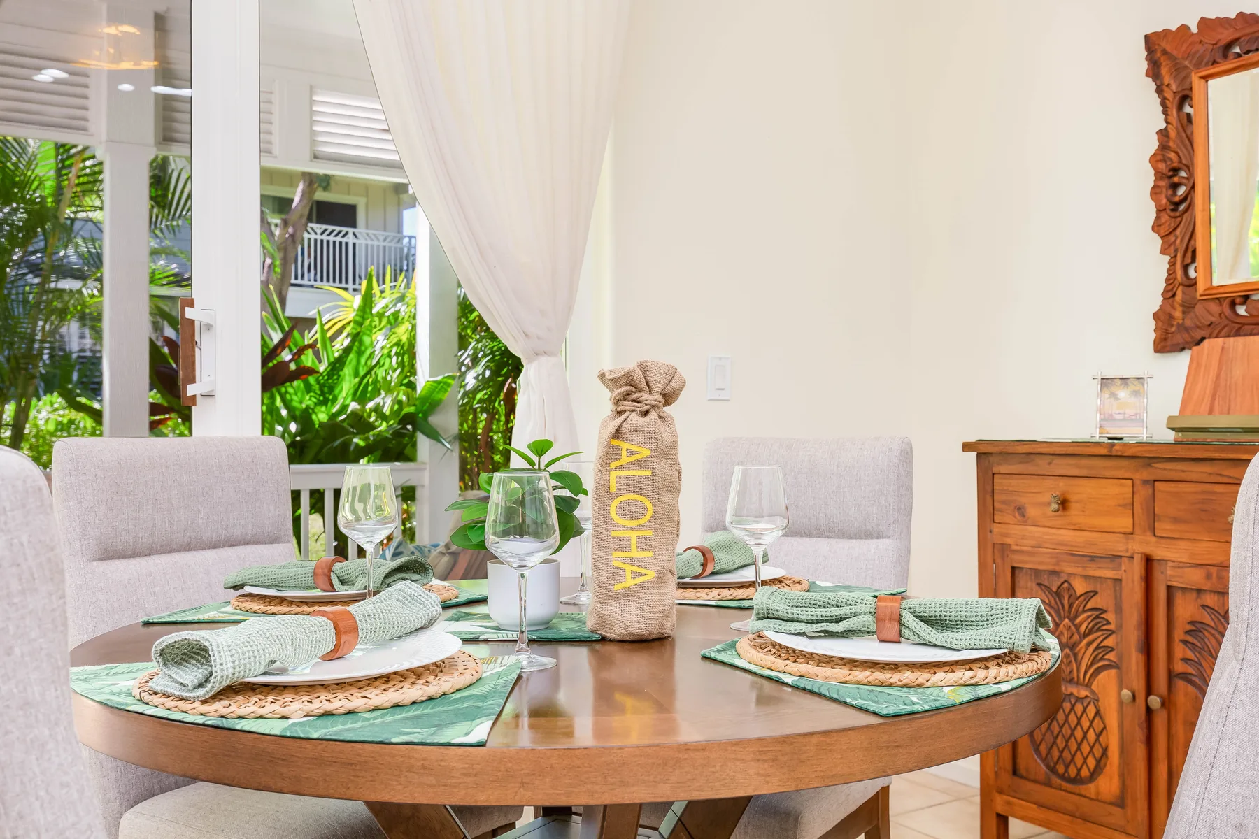 Un comedor con una mesa redonda preparada con manteles individuales y servilletas dobladas.