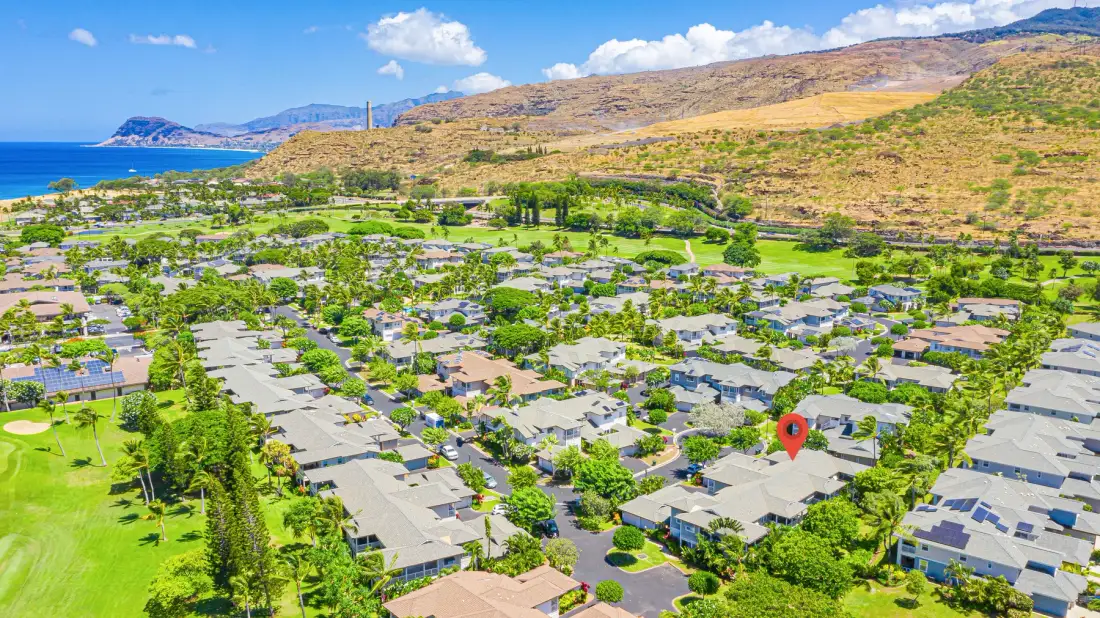 Vista aérea de un vecindario residencial con la costa y colinas a lo lejos.