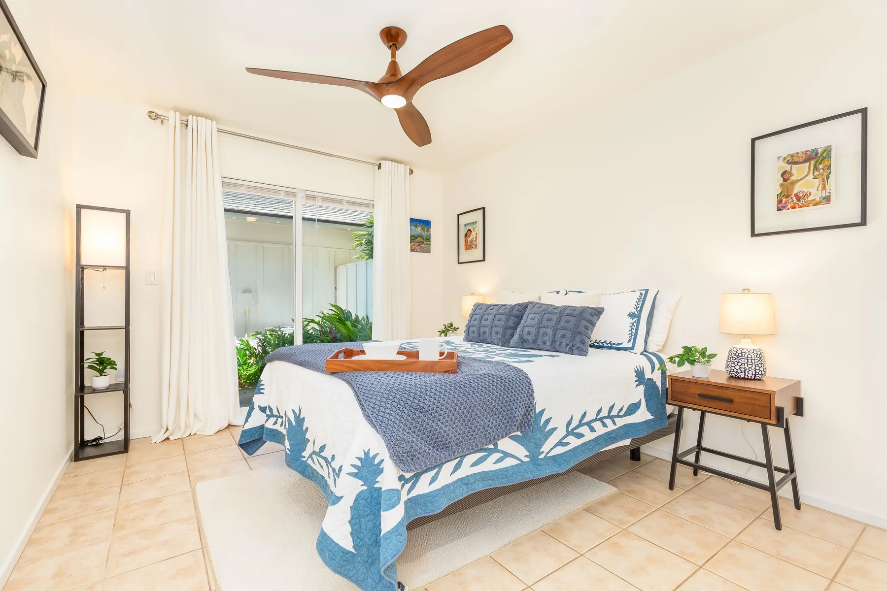 Un dormitorio luminoso con una cama vestida con ropa de cama azul y blanca.