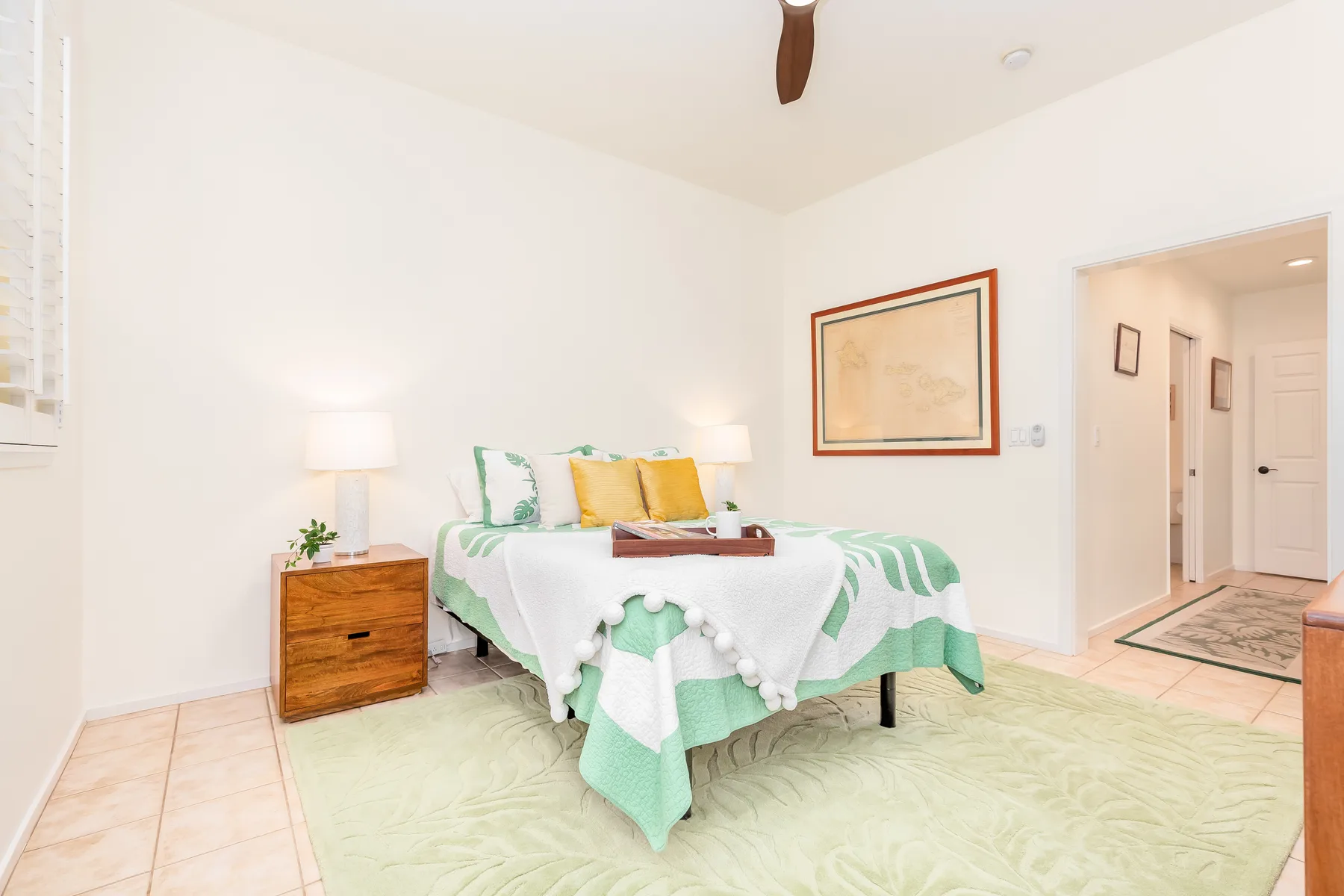 Un dormitorio luminoso con una cama vestida con ropa de cama verde y blanca.