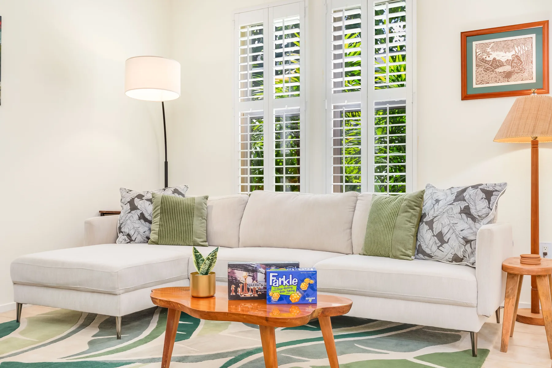 Una sala luminosa con sofá esquinero, mesa de centro de madera y ventanas con contraventanas.