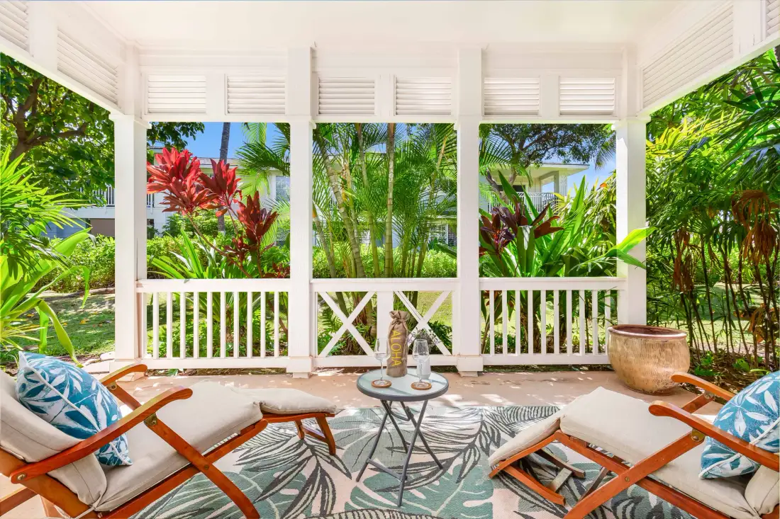 Una zona de estar exterior cubierta da a una exuberante vegetación tropical.