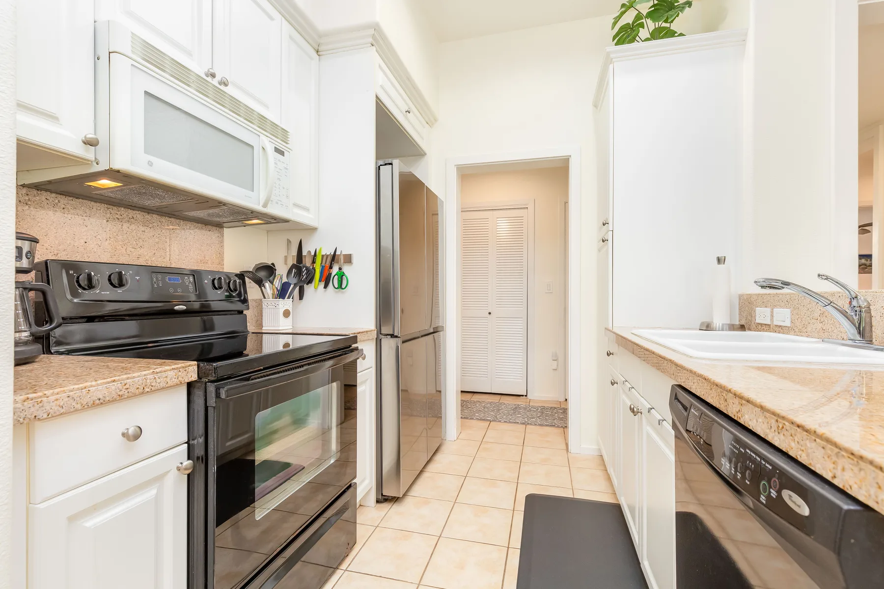 Una cocina luminosa con gabinetes blancos, una estufa y piso de baldosas.