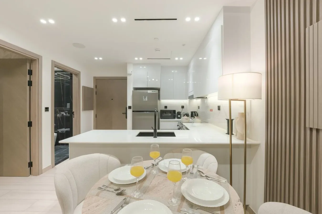 A bright modern kitchen and dining area with a white island and set table.