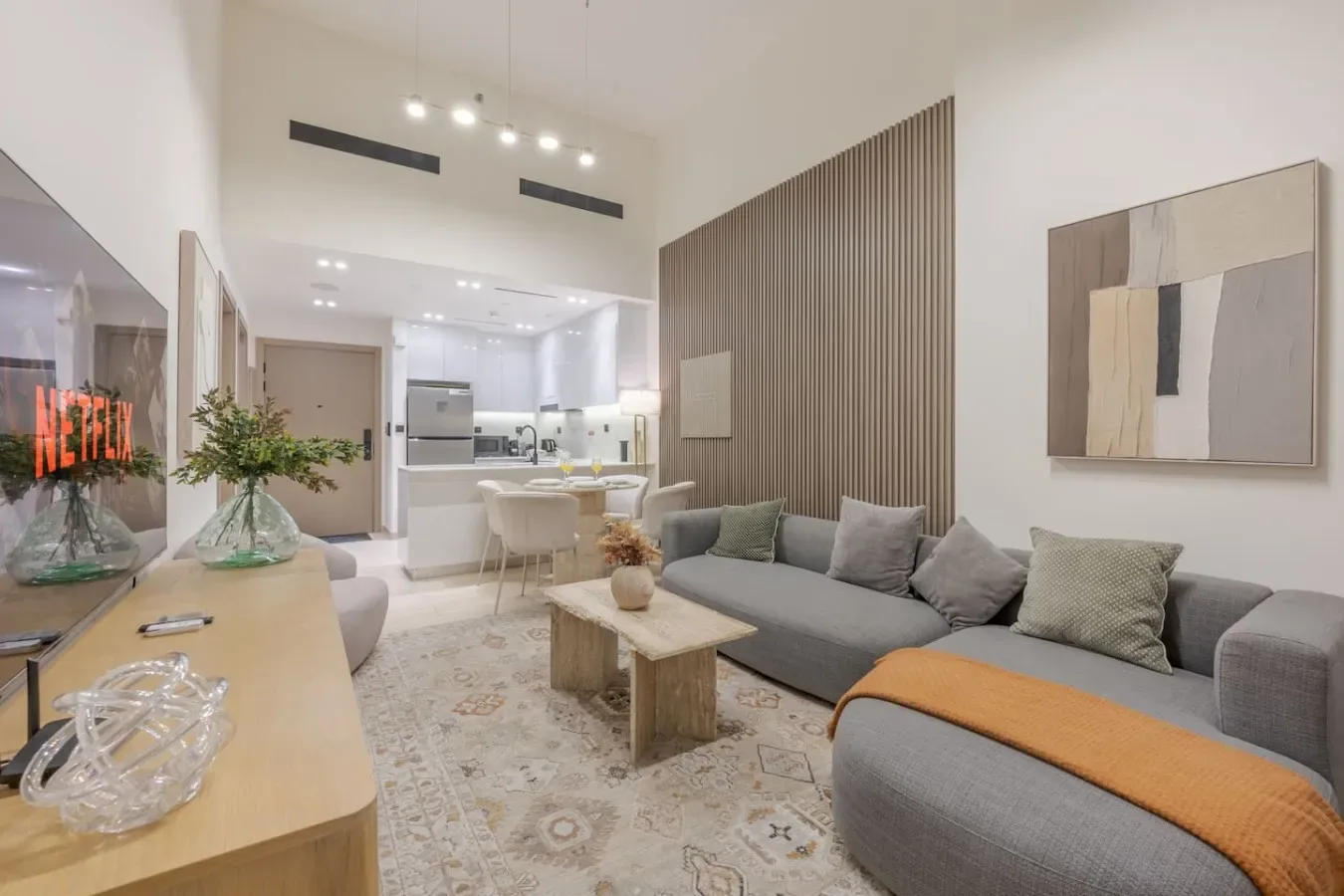A living room with gray seating and an open kitchen in the background.