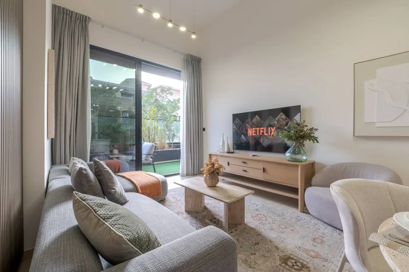 A bright living room with seating, a coffee table, and a television.