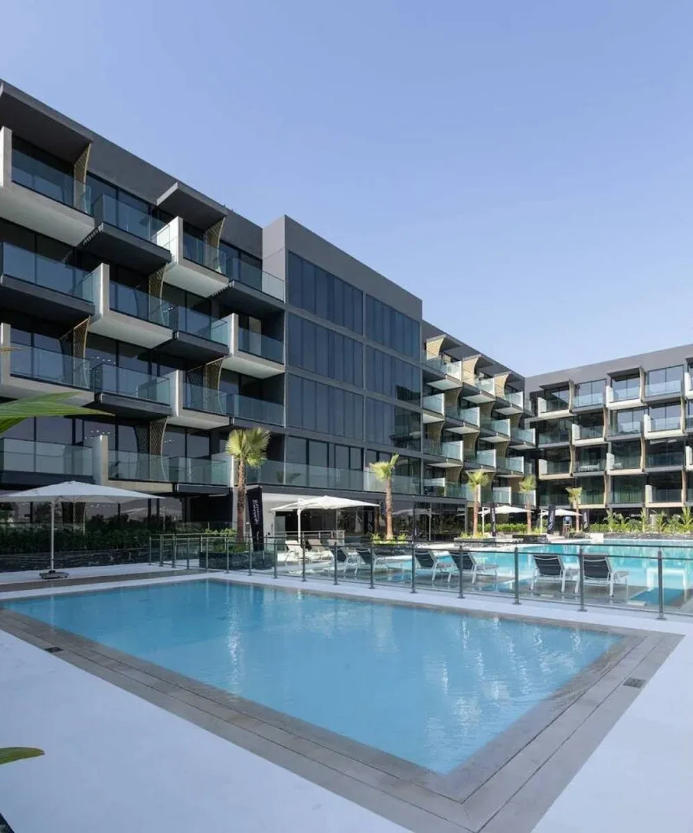 A swimming pool sits in the courtyard of a modern apartment building.