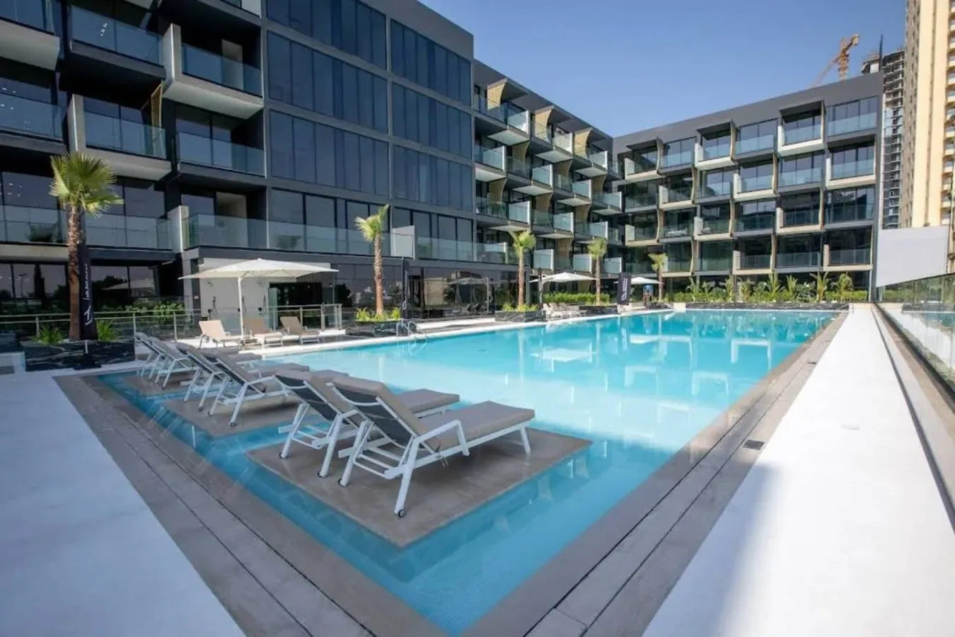 A large outdoor swimming pool beside a modern multi-story building.