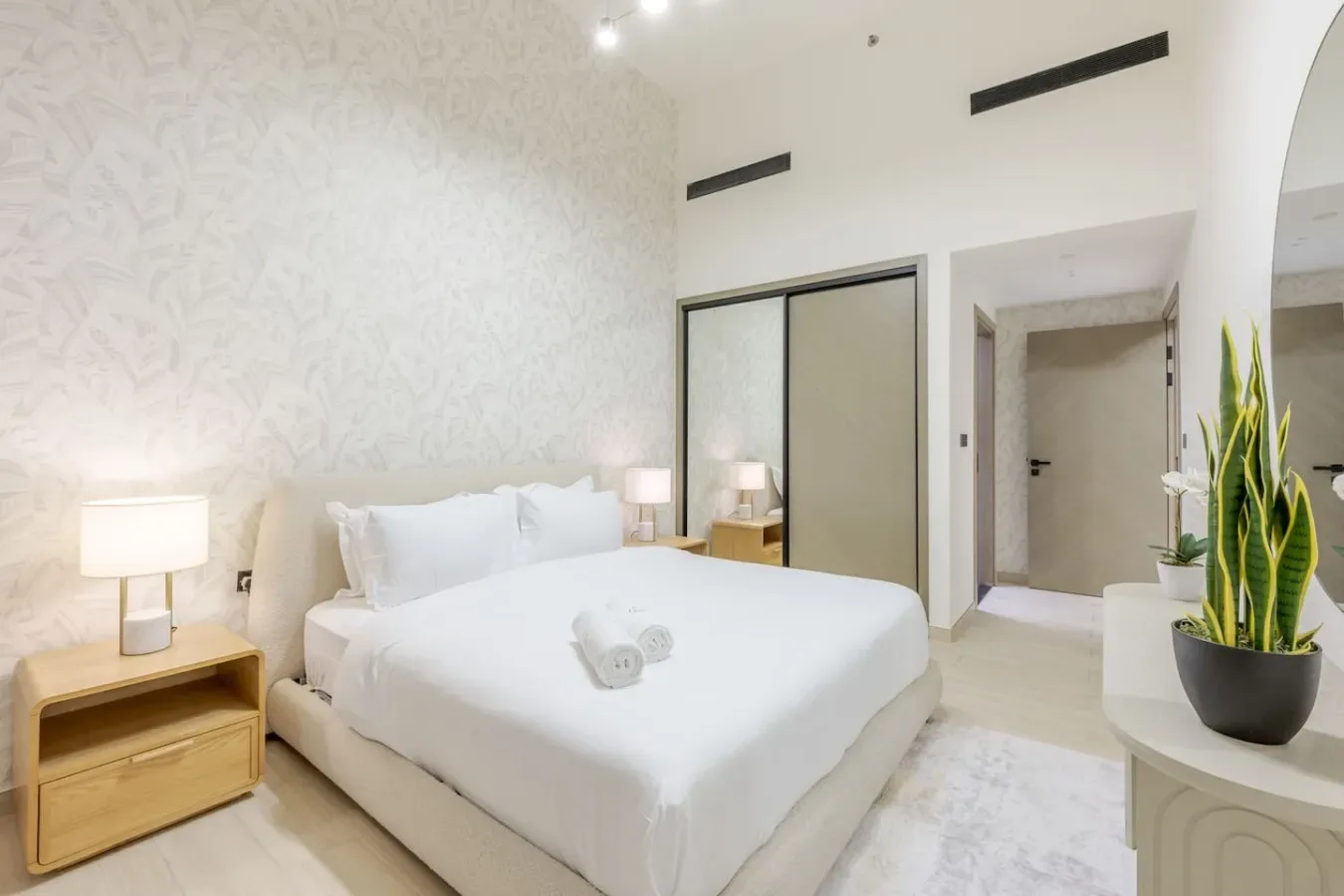 A bright bedroom with a neatly made bed and bedside tables.