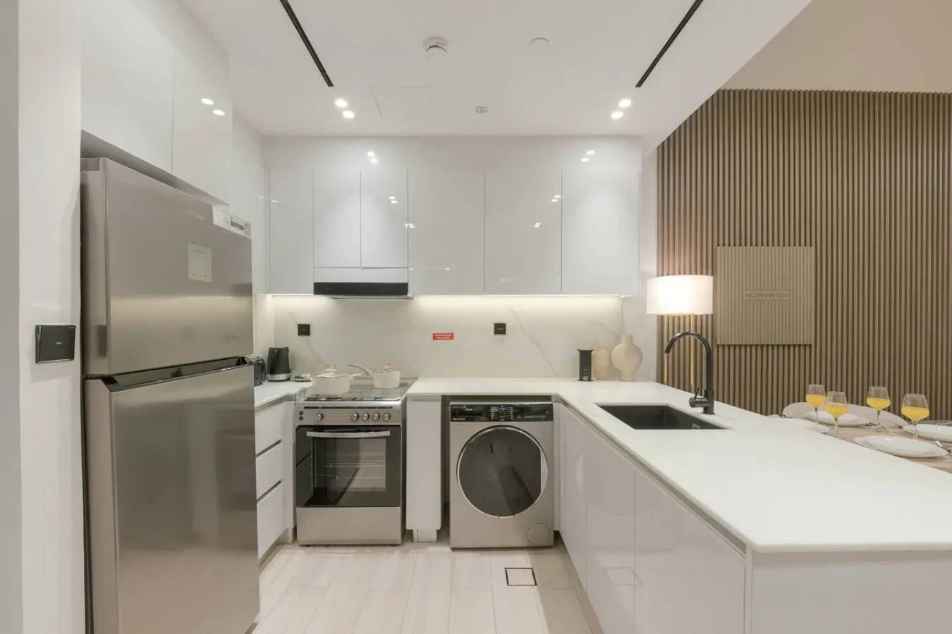 A modern kitchen with white cabinets, stainless steel appliances, and a long island.
