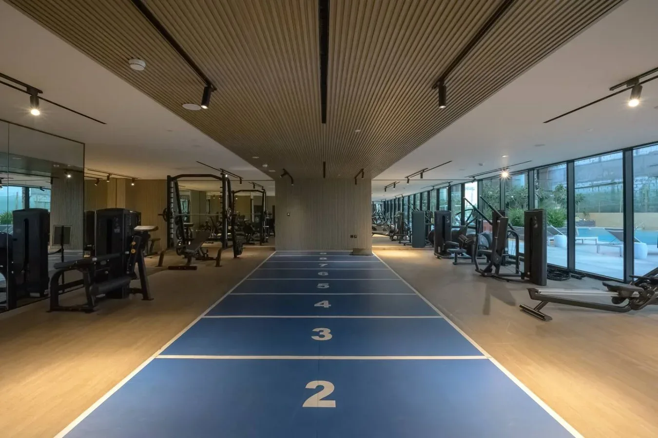 A gym with exercise equipment beside a blue indoor running track.