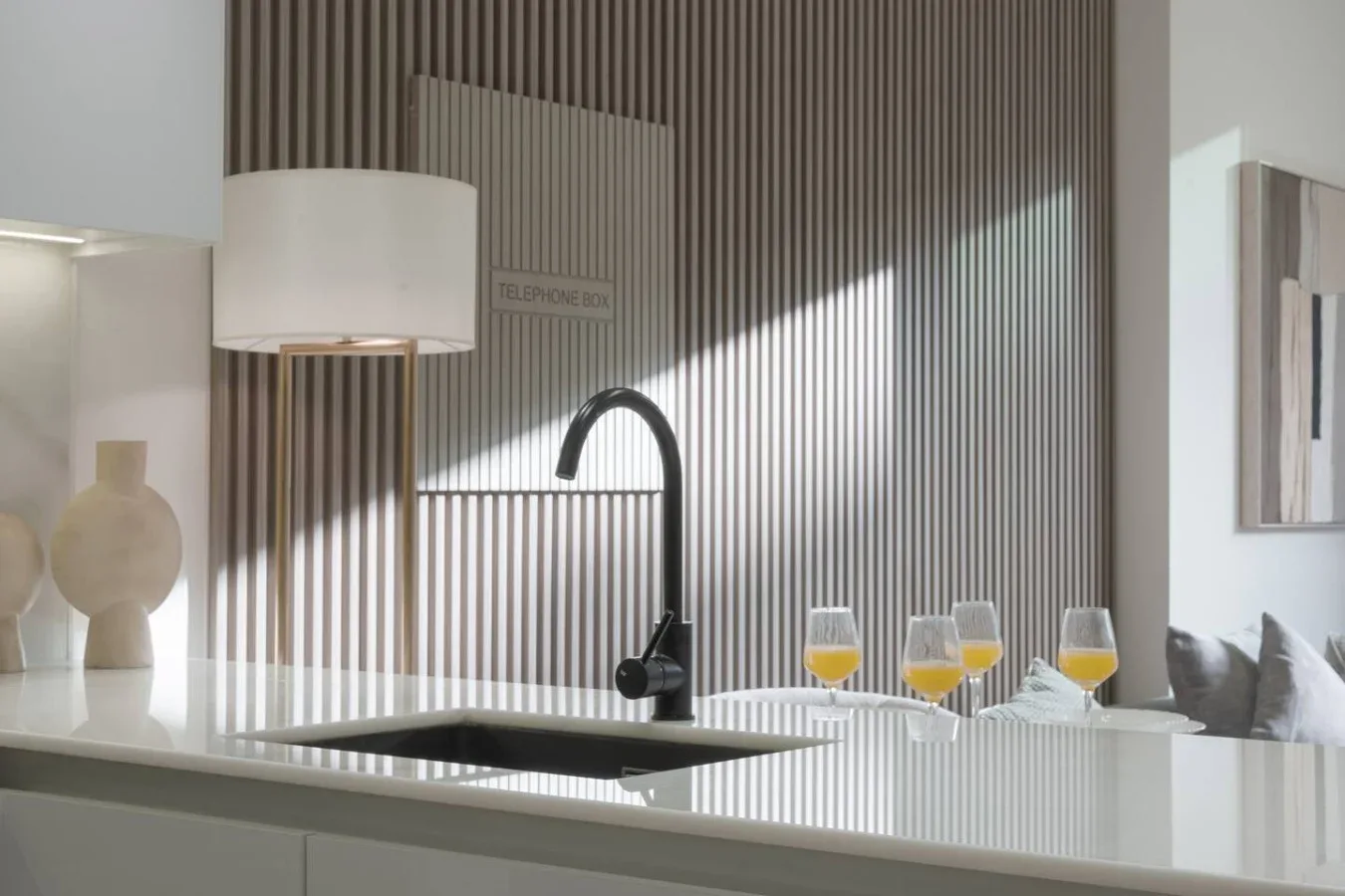 A modern kitchen counter with a dark sink and curved faucet.