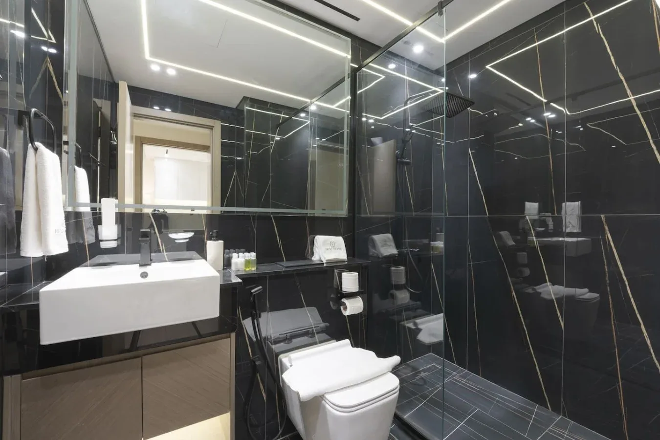 A modern bathroom with a sink, toilet, and glass-enclosed shower.