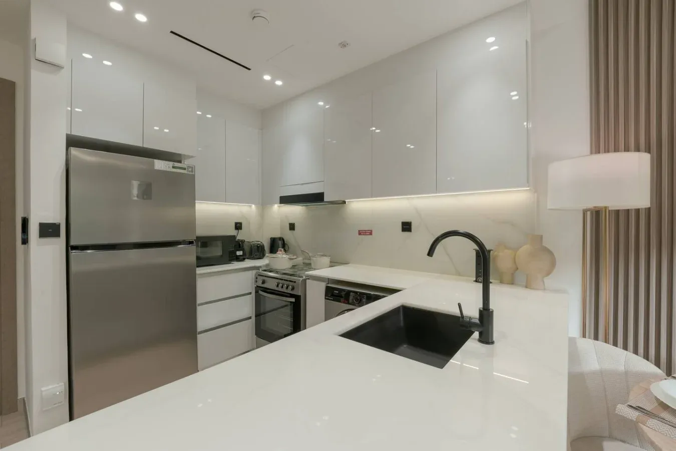 A modern kitchen with white cabinetry, stainless steel appliances, and a central island.