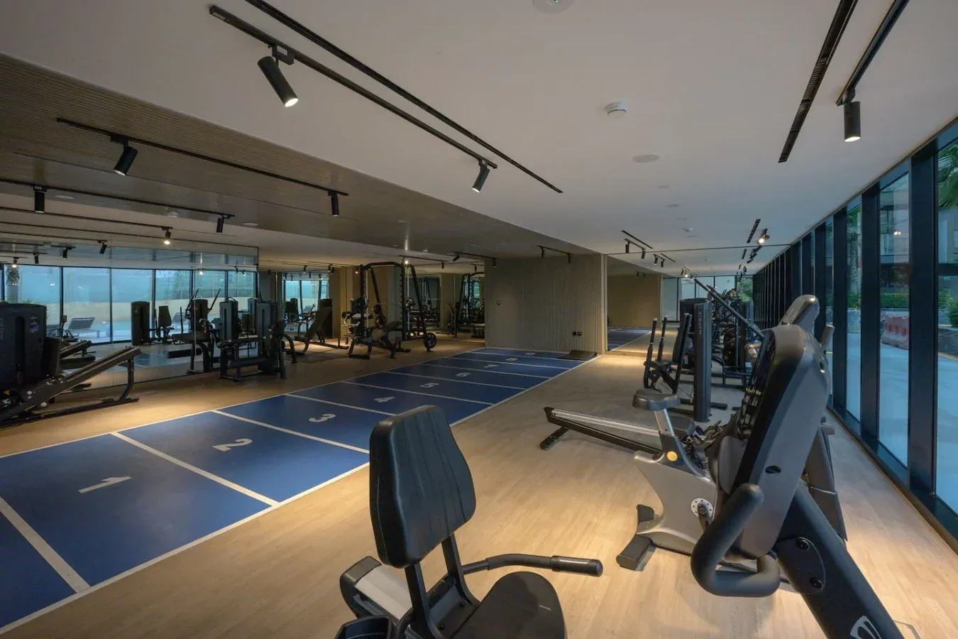 A gym with exercise machines beside a blue marked workout area.